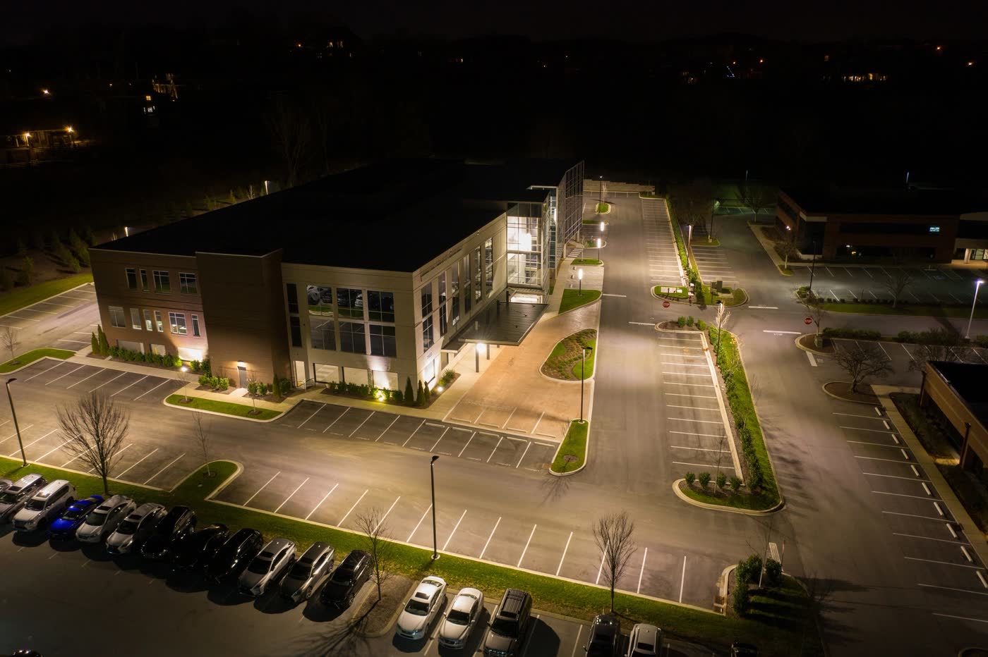 An office building and its parking lot after dark, from the air
